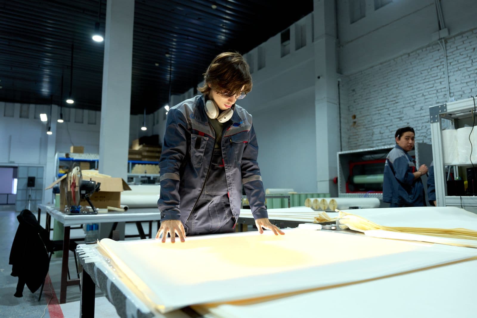 Factory worker checking material rolls against a logbook