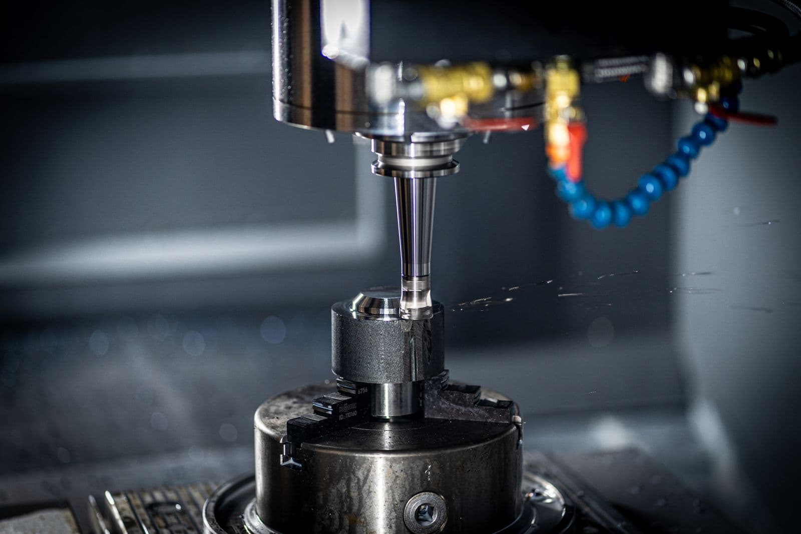 Close-up of a CNC machine spindle cutting metal with coolant spray