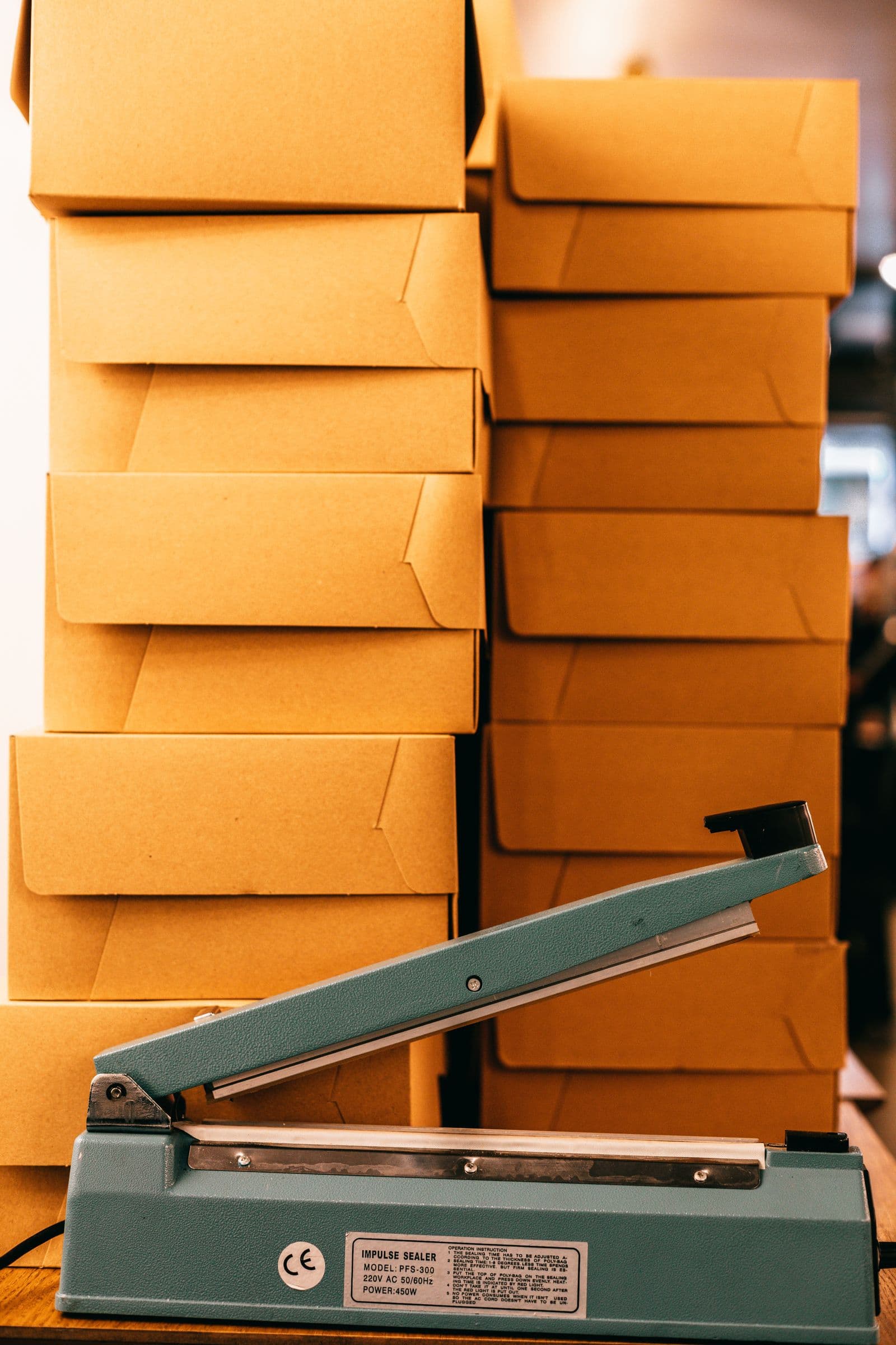 Bag sealing machine beside stacked cardboard boxes in a storehouse